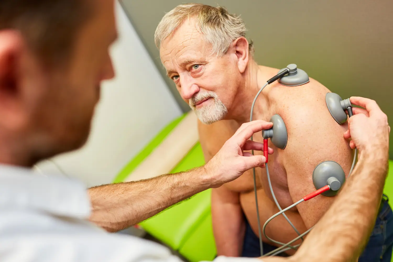 Orthopäde macht Reizstromtherapie bei älterem Patienten